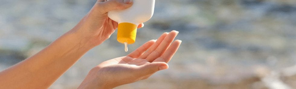 Woman's hands squeezing sunscreen out of a bottle