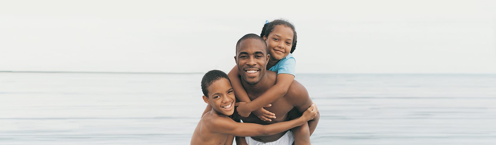 Man on beach with his children standing in front of the ocean