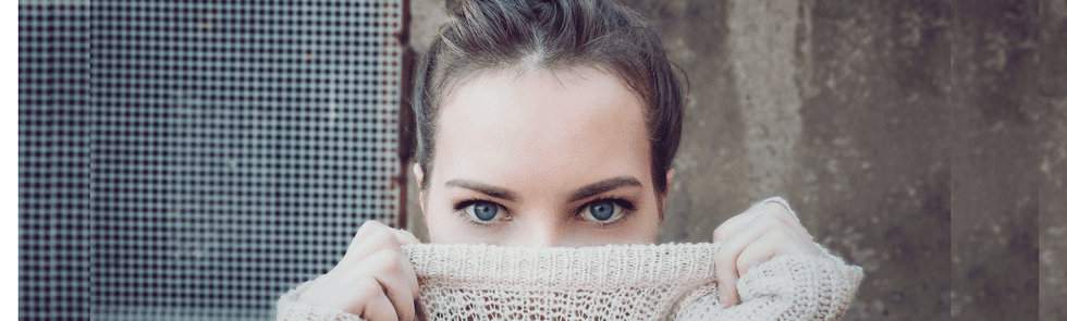 Woman hiding mouth by pulling her sweater up