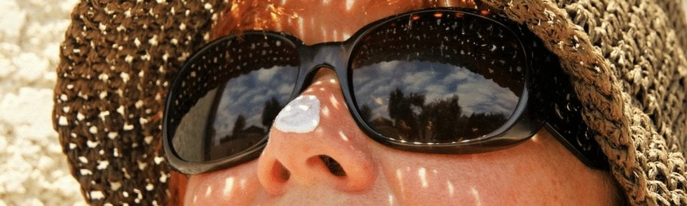 Close up of woman's face with sunglasses and sunscreen on her nose
