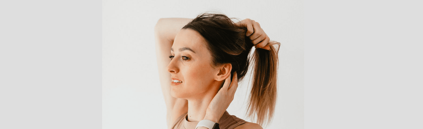 Woman pulling her hair back into a ponytail