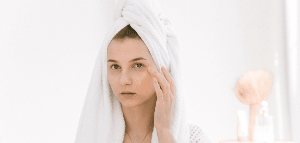 Woman with towel on her hair examining face skin
