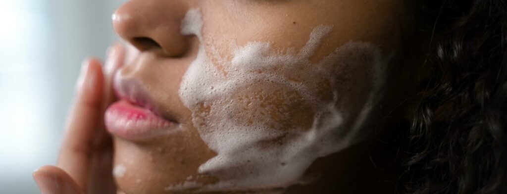 Close up of a woman washing her cheeks with skincare