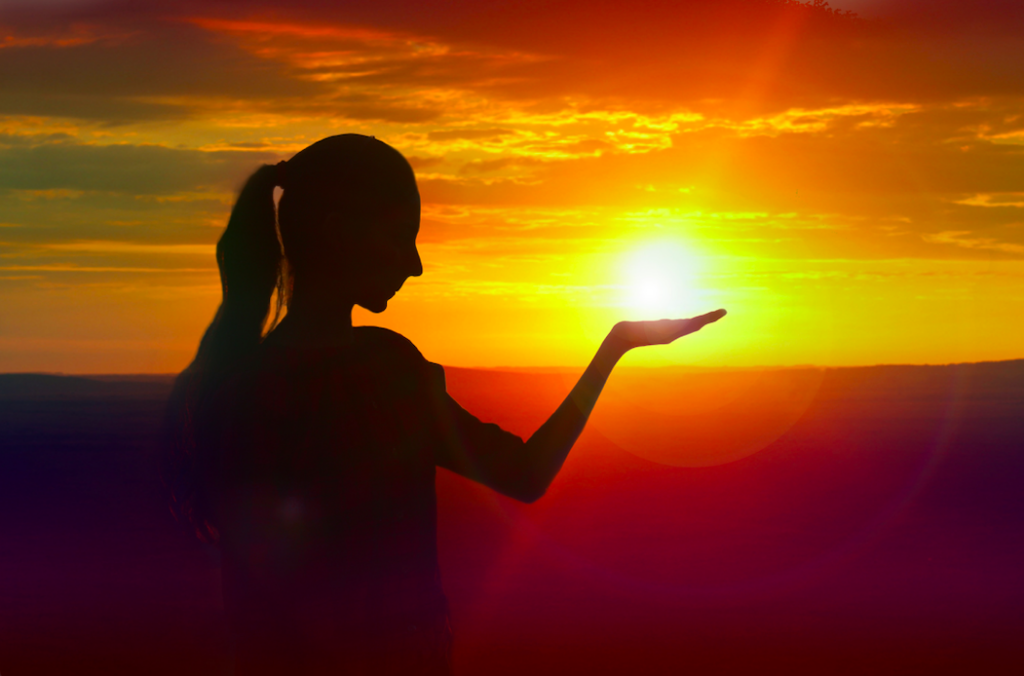 Woman pretending to hold the sunset in her hands