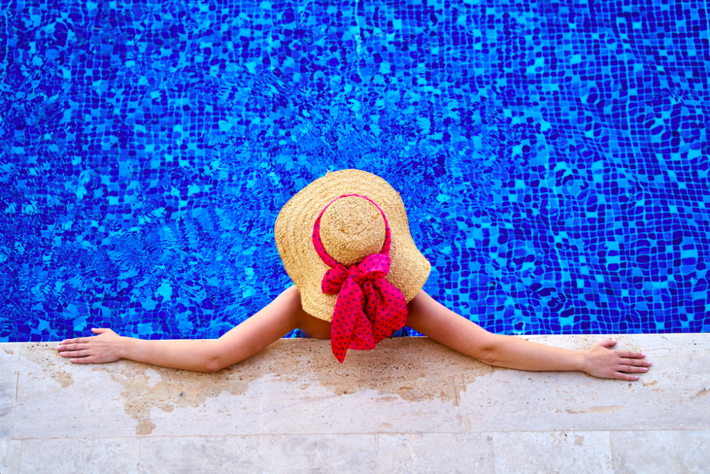 Ariel view of woman in the pool wearing a sun hat with a pink bow