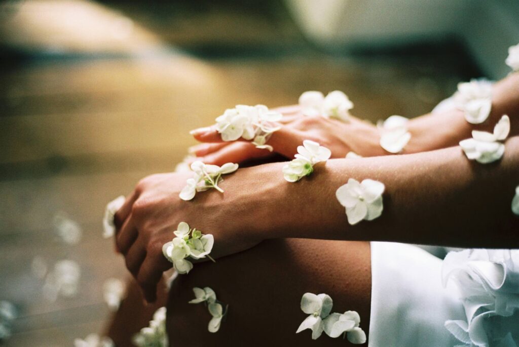 Arms with white flowers laying on top