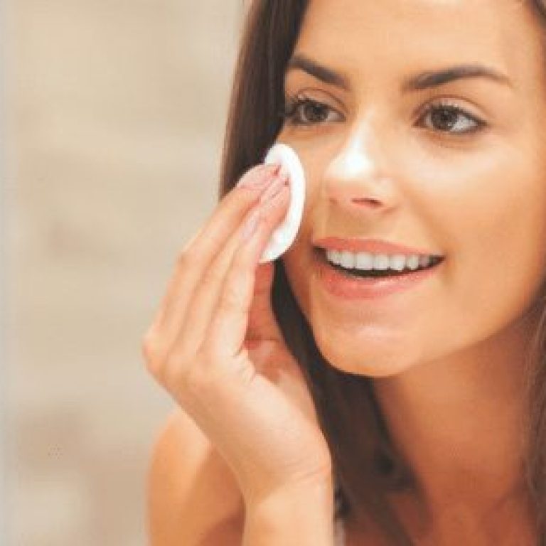 woman touching face with cotton pad