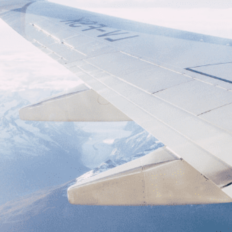 Airplane wing flying over mountains