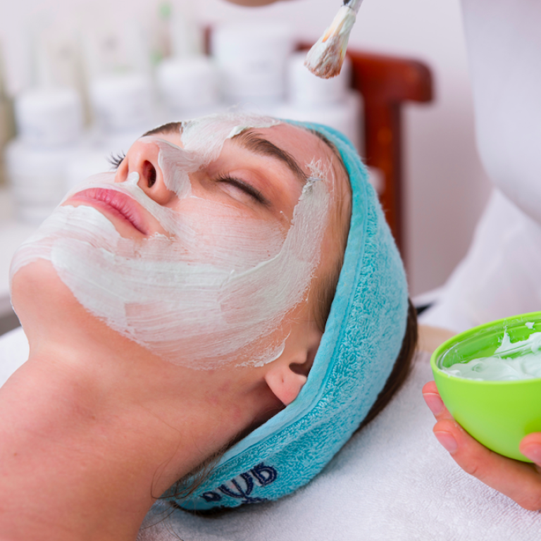 Woman getting a facial and having white medicine rubbed on her face