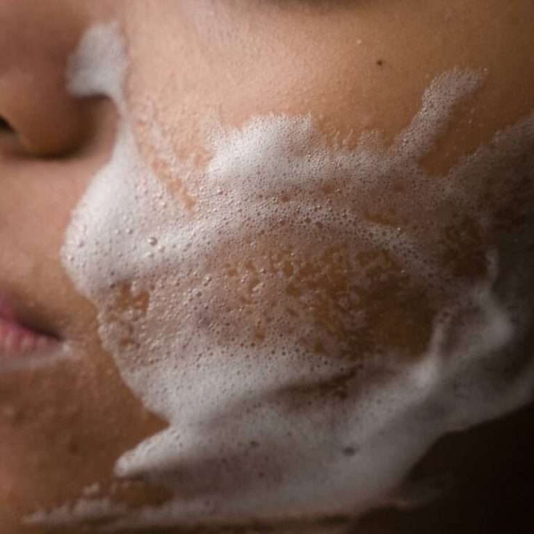 Close up of a woman washing her cheeks with skincare