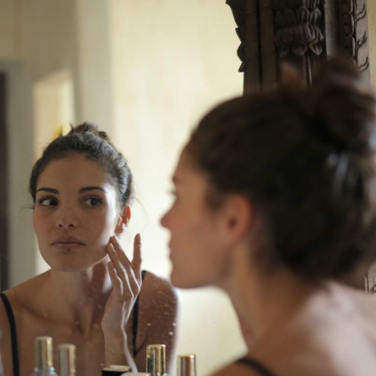 Woman examining skin in a mirror