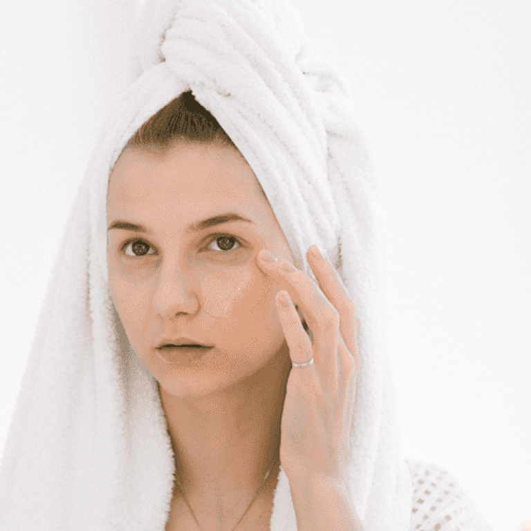 Woman with towel on her hair examining face skin