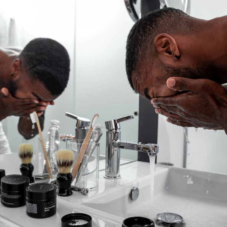 man washing face at sink