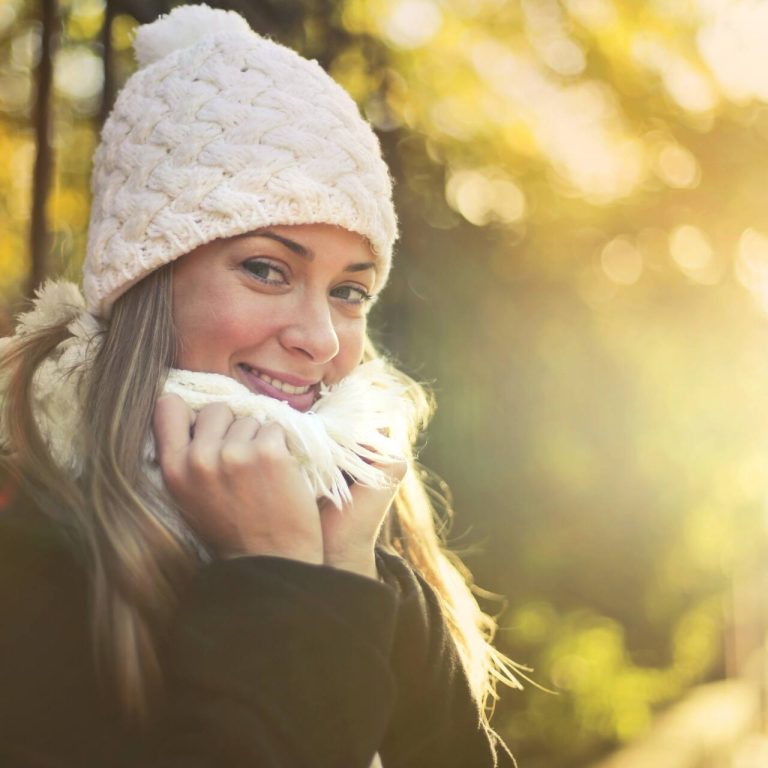 Girl outside wearing a white hat and scarf