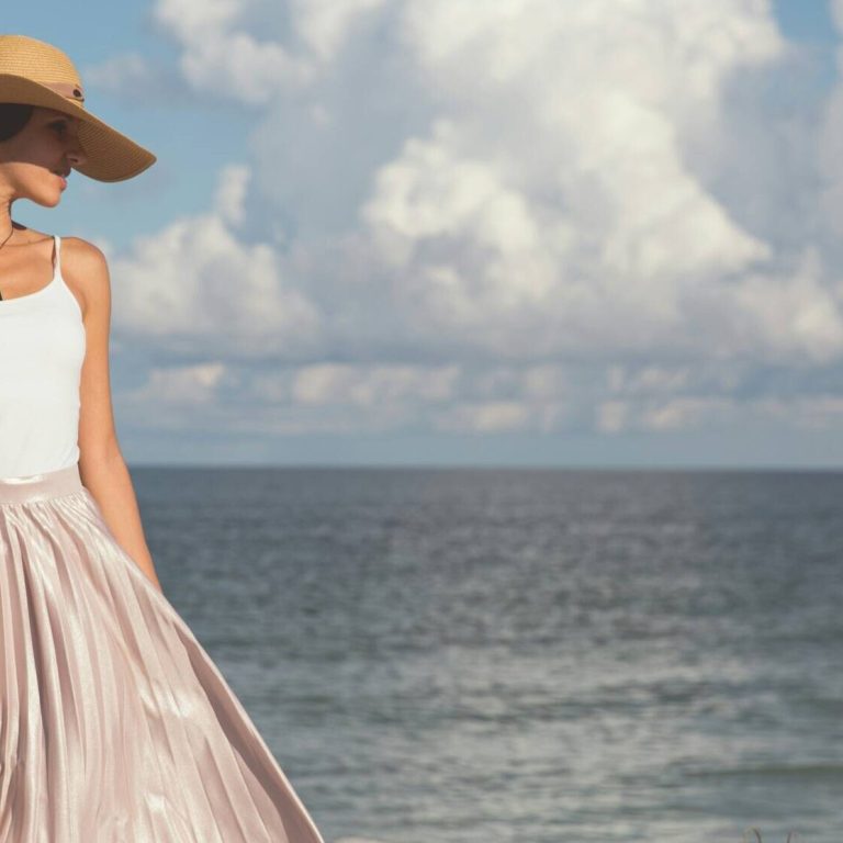 Woman in big sun hat walking on the beach