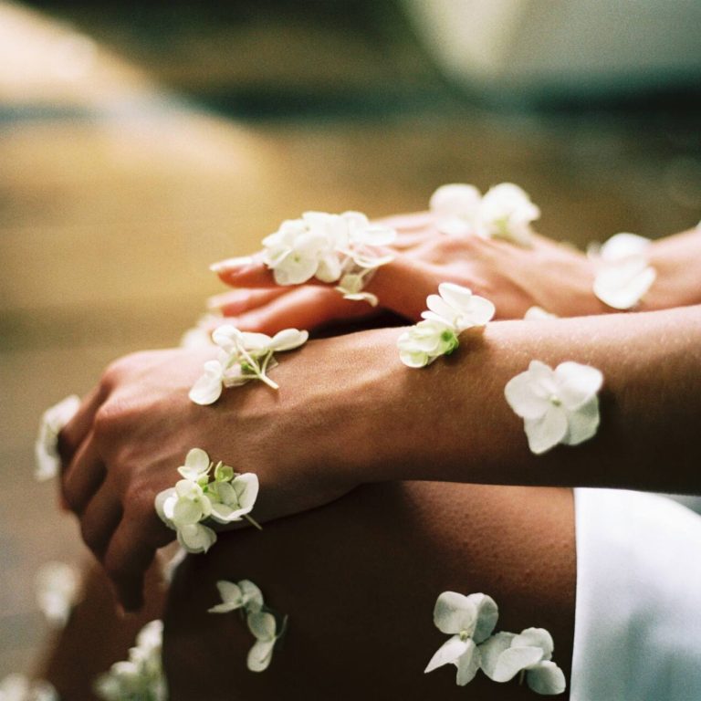 Arms with white flowers laying on top
