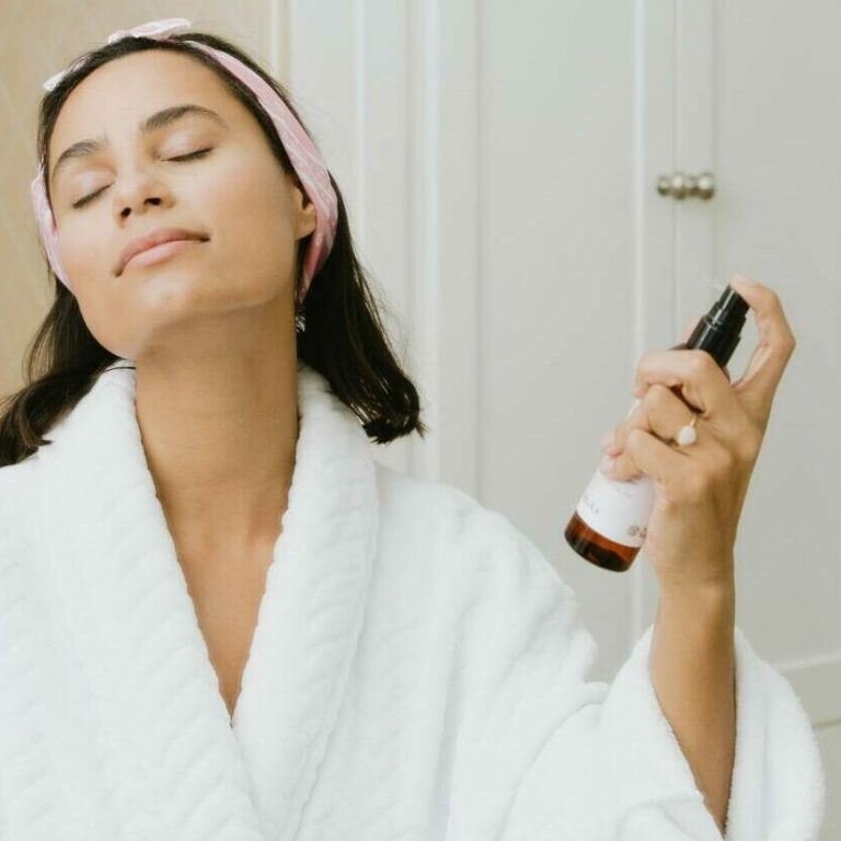 Woman spraying skincare on her face while getting ready