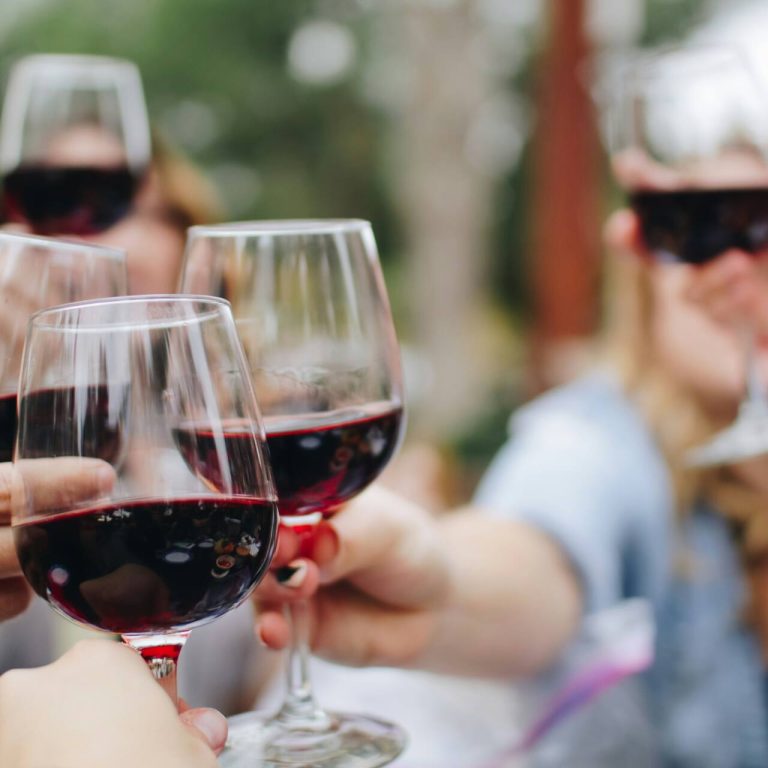 People cheering with red wine glasses
