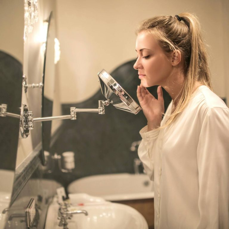 Woman examining chin and skin in the bathroom mirror