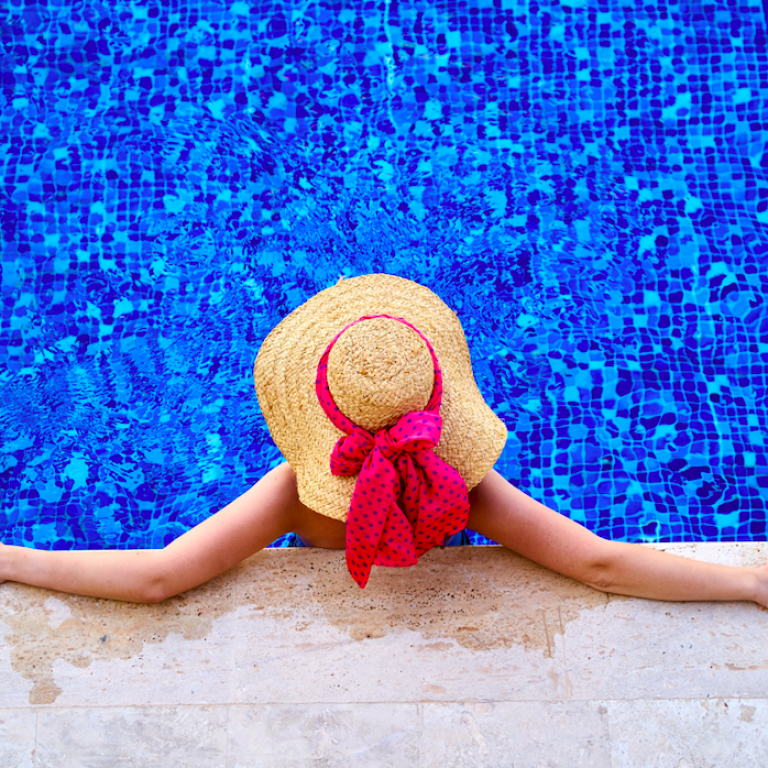 Ariel view of woman in the pool wearing a sun hat with a pink bow